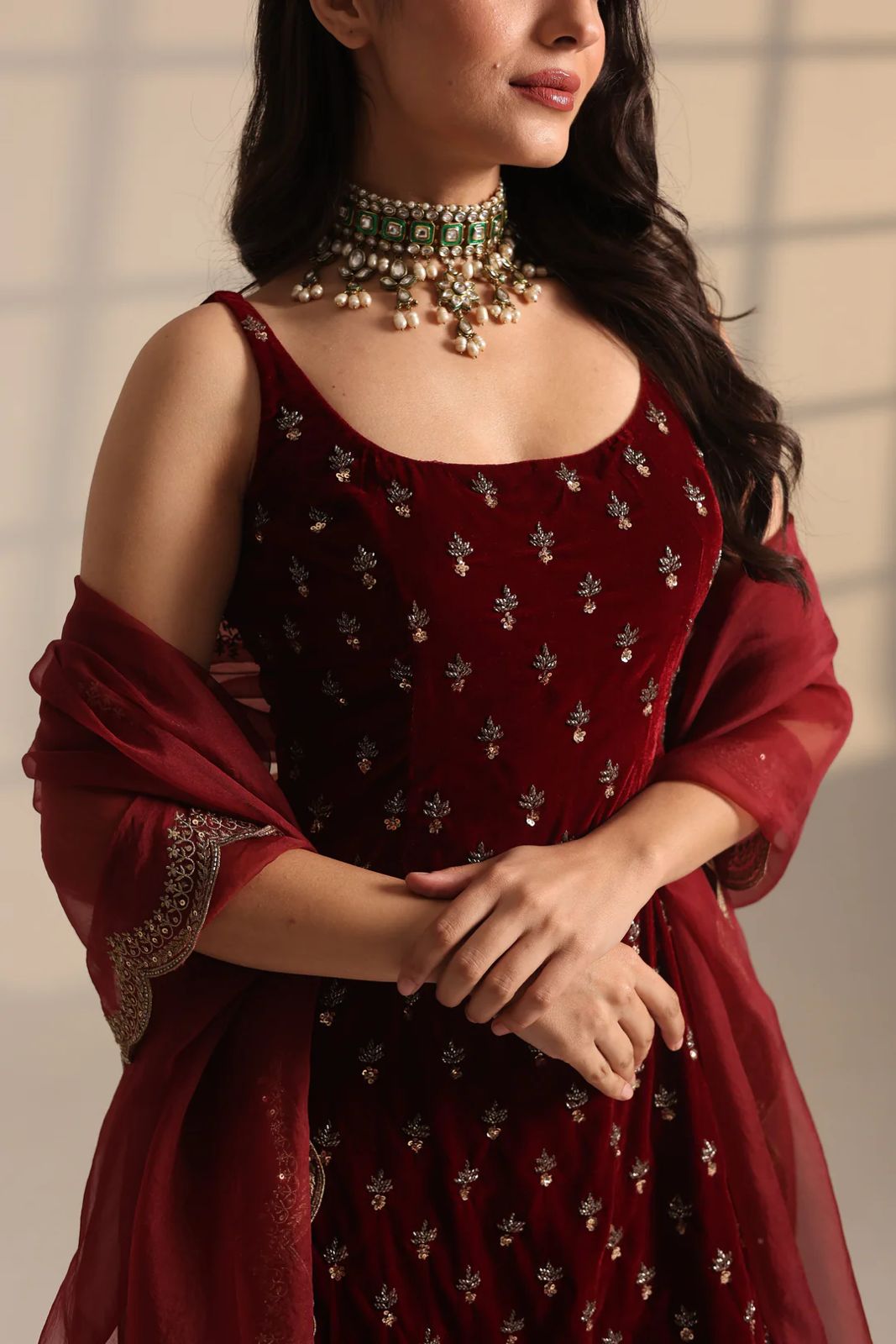 Maroon velvet Anarkali suit with gold embroidery and matching dupatta, styled with traditional choker necklace for festive occasions